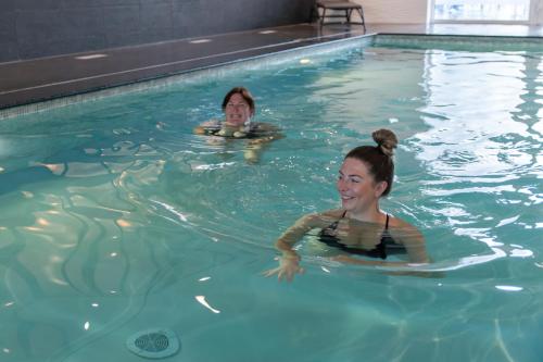 two women swimming in a swimming pool at ibis Styles Nieuwpoort in Nieuwpoort