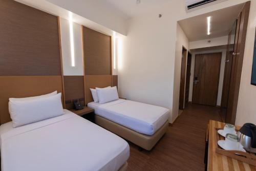 a hotel room with two beds and a table at Kabayan Hotel Pasay in Manila