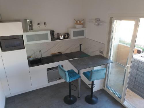 une cuisine avec un comptoir et deux chaises bleues dans l'établissement Le Miroir, au Cap d'Agde