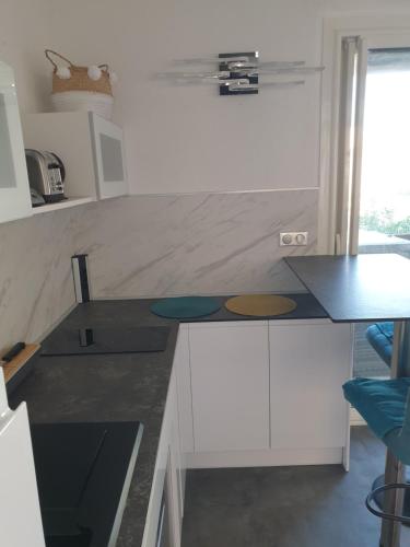 une cuisine avec des armoires blanches et un comptoir dans l'établissement Le Miroir, au Cap d'Agde