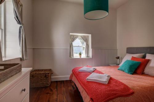 a bedroom with a bed with a red blanket and a window at Prues Cottage in Port Fairy