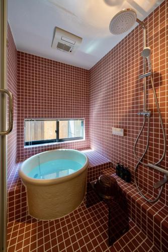 a bathroom with a tub in a red tiled wall at Shiori Machiya House in Kanazawa