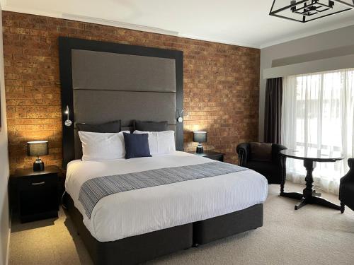 sypialnia z dużym łóżkiem i ceglaną ścianą w obiekcie Federation Motel Resort - Corowa w mieście Corowa
