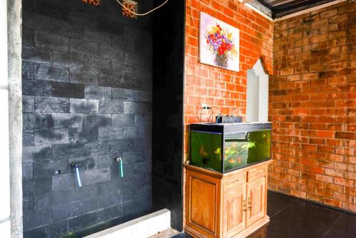 un bagno con vasca per pesci in un muro di mattoni di Urbanview Hotel Syariah Prambanan by RedDoorz a Yogyakarta