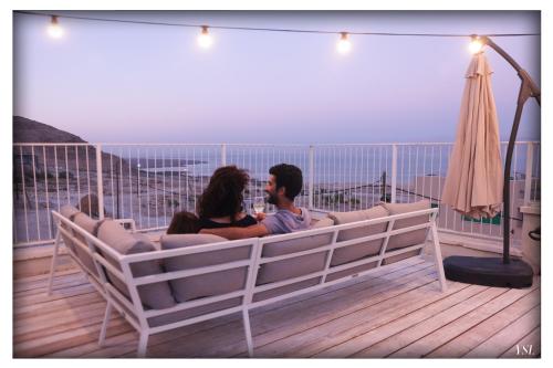 a man and woman sitting on a couch on a balcony at Dead Sea Rooftop - גג ים המלח in Ovnat