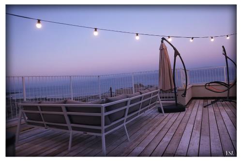 a balcony with an umbrella and a string of lights at Dead Sea Rooftop - גג ים המלח in Ovnat