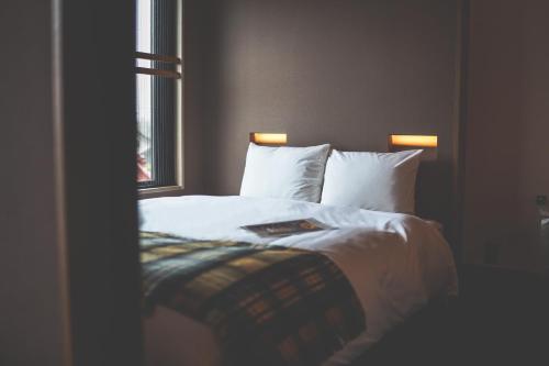 a bedroom with a bed with white sheets and a window at Twin-Line Hotel Karuizawa Japan in Karuizawa