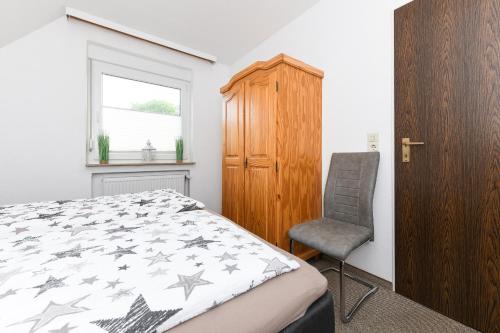 1 dormitorio con 1 cama, 1 silla y 1 ventana en Ferienwohnung Haus Boje "Knurrhahn", en Neuharlingersiel