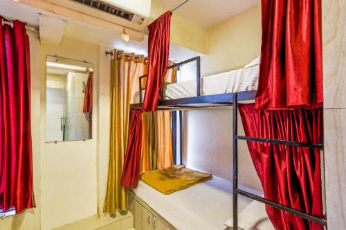 Cette chambre comprend 2 lits superposés dotés de rideaux rouges. dans l'établissement BKC Dormitory Bandra East, à Mumbai