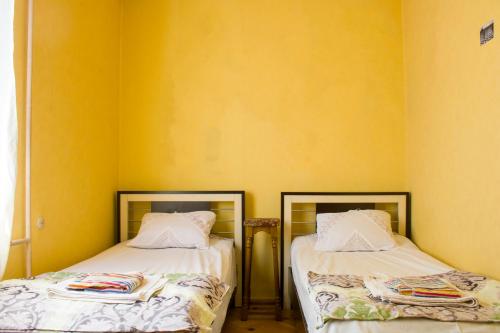 two beds in a room with yellow walls at Nino's Guest House in Tbilisi City