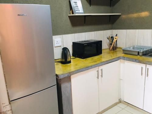 a kitchen with a refrigerator and a microwave on a counter at Asante’s Guest House in Calcutta