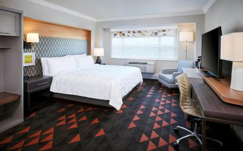 a hotel room with a bed and a desk and a television at Holiday Inn & Suites Oakville at Bronte, an IHG Hotel in Oakville