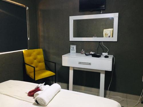 a bedroom with a white desk and a yellow chair at Asante’s Guest House in Calcutta