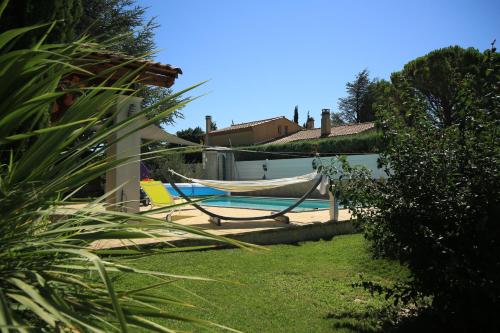 a pool with a hammock next to a house at Chalet Mont Ventoux et Chalet VIP in Camaret-sur-Aigues