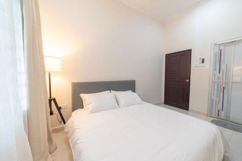 a white bed in a white room with a window at HILMERA Guesthouse in Kuantan