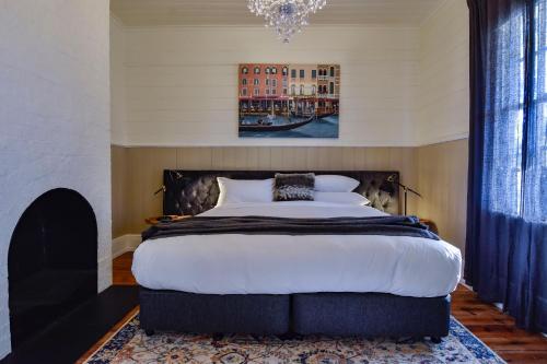 Un dormitorio con una cama grande y una lámpara de araña. en Heritage Cottage Daylesford, en Daylesford
