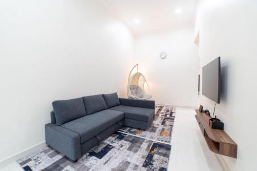 a living room with a couch and a tv at HILMERA Guesthouse in Kuantan