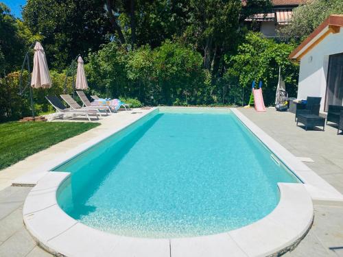 a swimming pool with blue water and chairs and umbrellas at Appartamento con giardino, La Casa di G&G in Marina di Carrara