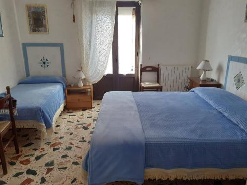 een slaapkamer met 2 bedden en een raam bij Affittacamere GERANI in Capizzi