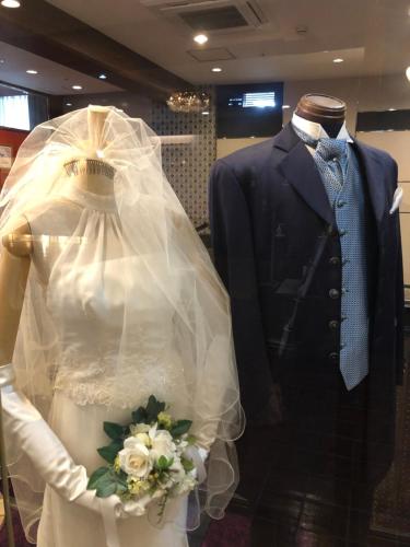a wedding dress and a suit in a store window at Highness Hotel Kurume in Kurume