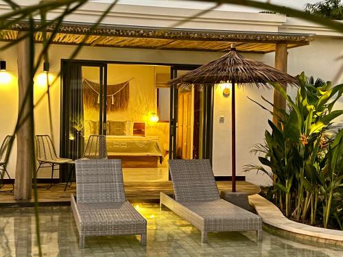 a bedroom with a bed and two chairs and an umbrella at Kalia Bingin - Adult only in Uluwatu
