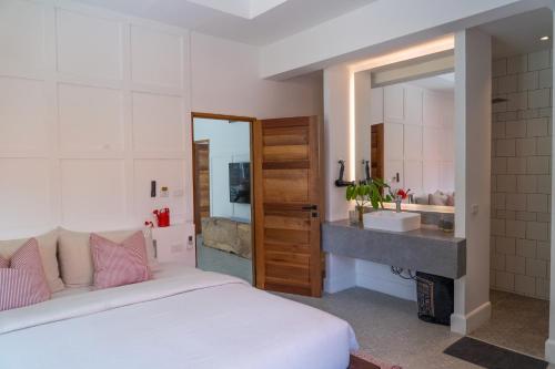 a bedroom with a bed and a bathroom with a sink at THALEMAAN POOL VILLA in Koh Samui 