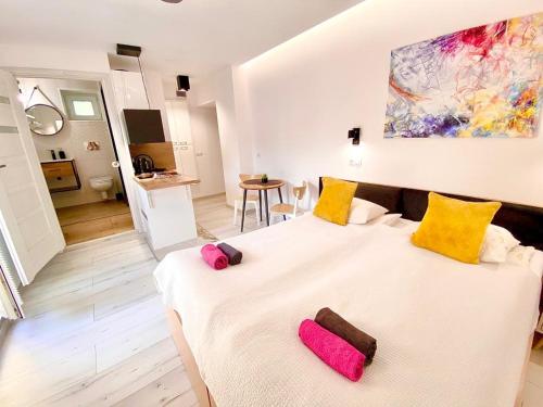 a bedroom with a large white bed with yellow and pink pillows at SKALNY apartamenty, pokoje in Ogrodzieniec
