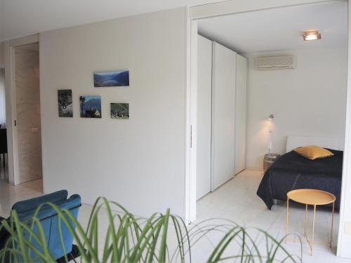 ein weißes Schlafzimmer mit einem Bett und einem Tisch in der Unterkunft Alice Holiday Apartment in Locarno