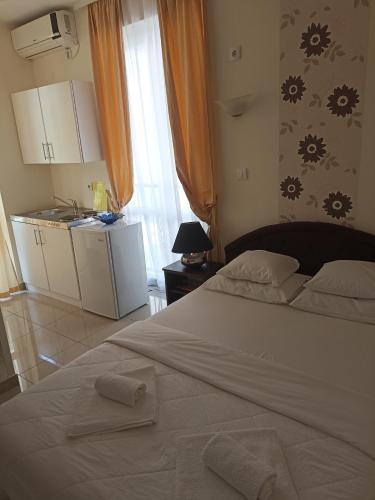 a bedroom with a large white bed and a kitchen at Swiss Residence Montenegro in Herceg-Novi
