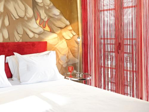 a bedroom with a white bed and a red wall at Grecotel Pallas Athena in Athens
