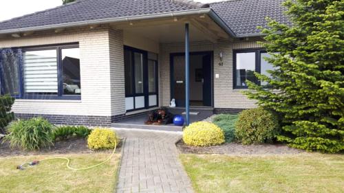 a dog sitting on the porch of a house at Haus Kenzo 65348 in Moormerland