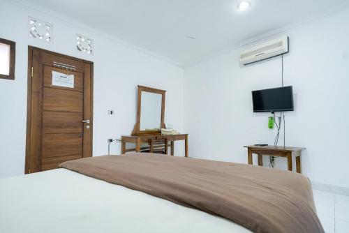 a bedroom with a large bed and a television at Urbanview Hotel Syariah Ratu Kuring Gisting by RedDoorz in Banjarnegeri