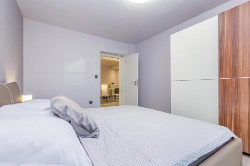 a white bedroom with a bed and a sliding glass door at Bellona in Malinska