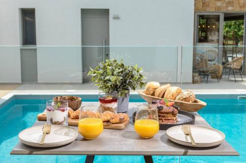 een tafel met een dienblad met ontbijtproducten en sinaasappelsap bij Soho Exclusive Suites in Skala Potamias