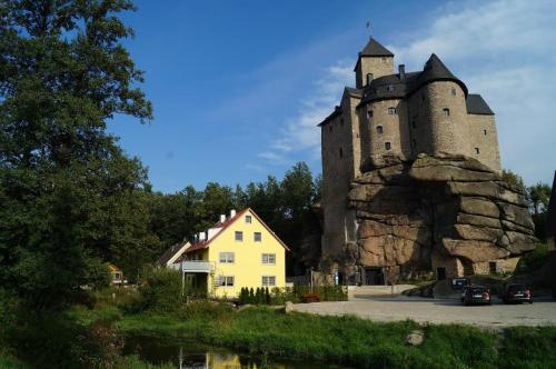 a castle with a yellow house in front of it at Ferienwohnung und Sommerhaus unter der Burg in Falkenberg