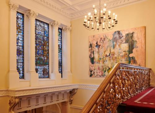 a staircase in a building with a painting and a chandelier at Gleneagles Townhouse in Edinburgh