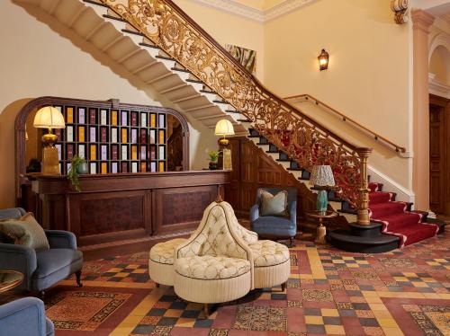 a living room with a staircase with chairs and a couch at Gleneagles Townhouse in Edinburgh