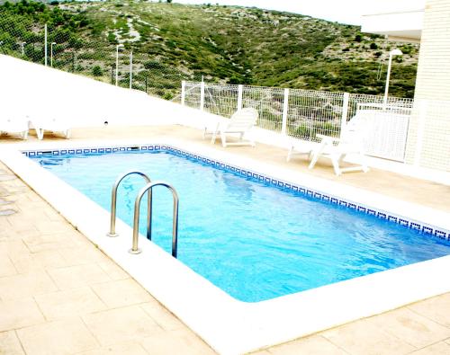 - une piscine avec 2 chaises à côté d'une maison dans l'établissement Adosado con fantásticas vistas al mar y piscina., à Peñíscola