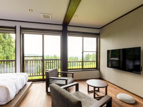 a bedroom with a bed and a balcony with windows at kamosu mori in Tokamachi