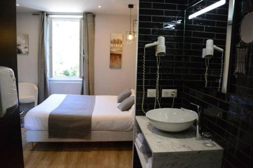 a bedroom with a bed and a bathroom with a sink at Hotel Restaurant de la Poste in Saint-Just-en-Chevalet