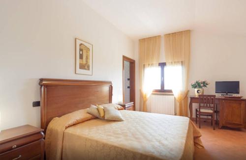 a bedroom with a bed and a desk and a television at CASCINA TABACHERA x10 Vineyard House - GARDA LAKE in Pozzolengo