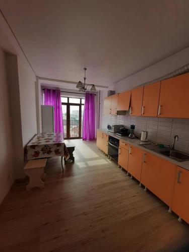 a kitchen with orange cabinets and purple curtains at Diplomat 3 in Bishkek