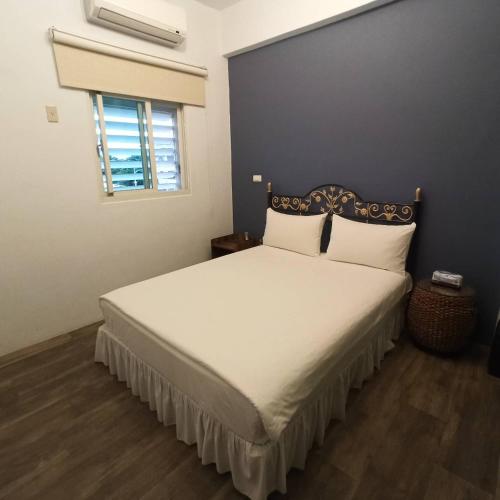 a bedroom with a large bed with white sheets and a window at 玖拾捌民宿-98bnb in Hualien City