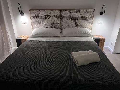 a large bed with a black blanket and a pillow on it at Villa Chiara Taormina in Taormina