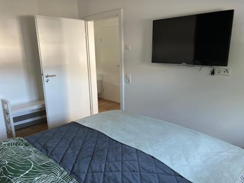 a bedroom with a bed with a flat screen tv on the wall at BeeHome Euskirchen in Euskirchen