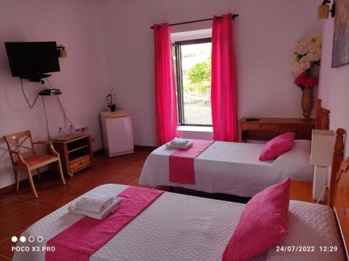 een slaapkamer met 2 bedden en een raam met roze gordijnen bij Numero28,Casa Tilama in Uga