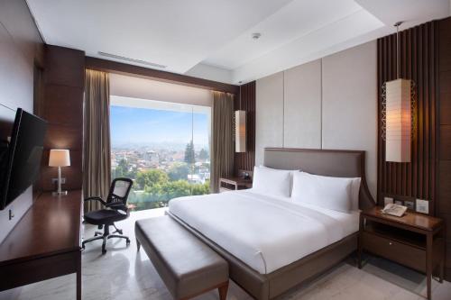 a bedroom with a bed and a desk and a window at Holiday Inn Bandung Pasteur by IHG in Bandung