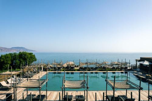 basen z krzesłami i ocean w tle w obiekcie La Mer Resort & Spa - Adults Only w mieście Georgioupolis