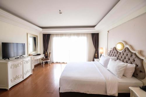 a hotel room with a large bed and a television at LK Miracle Suite - SHA Extra Plus in Pattaya South