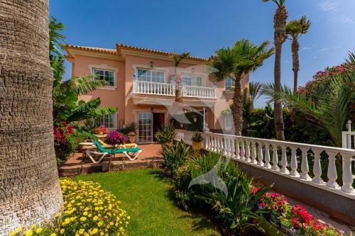 una casa con una valla blanca y flores en Apartamentos Los Delfines, en El Médano
